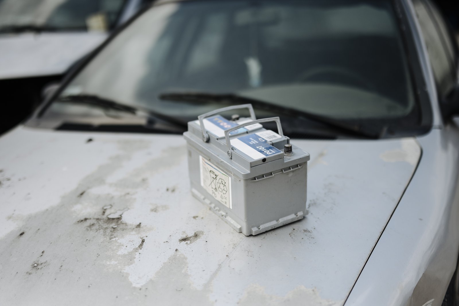 12-volt car battery sitting on a vehicle hood during replacement